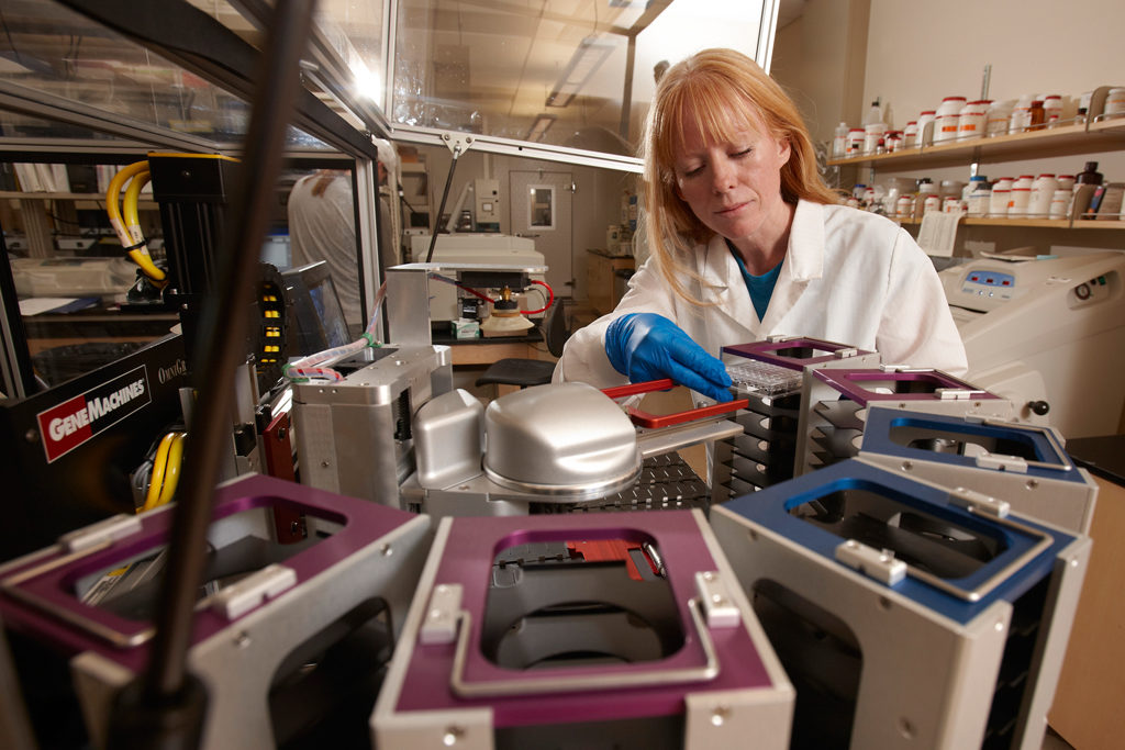 A lab technician retrieves samples from a tower like device.